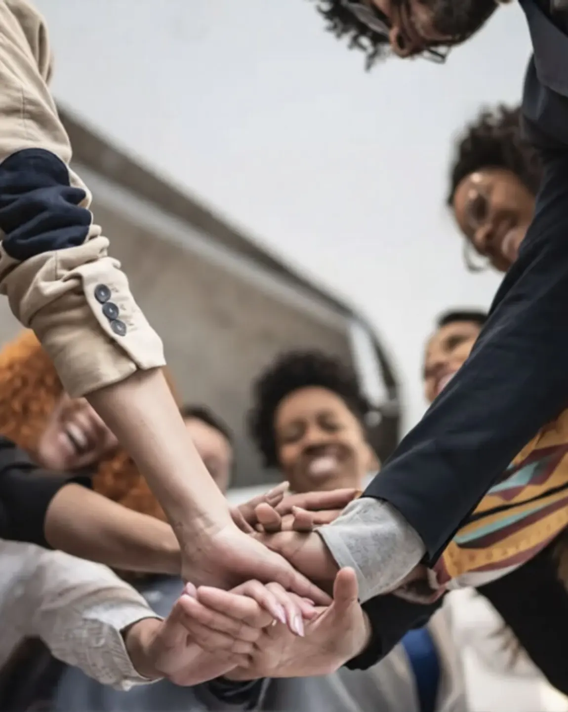 A group of people standing in a circle with their hands joined in the middle