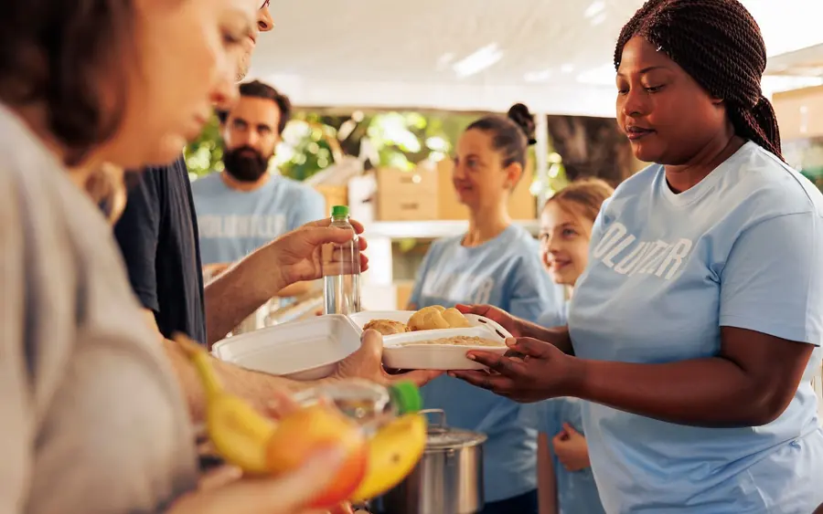 Volunteers serving and handing out food to families at a community meal
